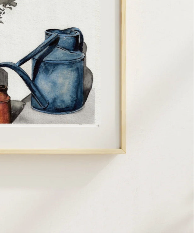 Watering Can” framed in a natural wood frame, an original watercolour painting by Shanaz Minhas. 