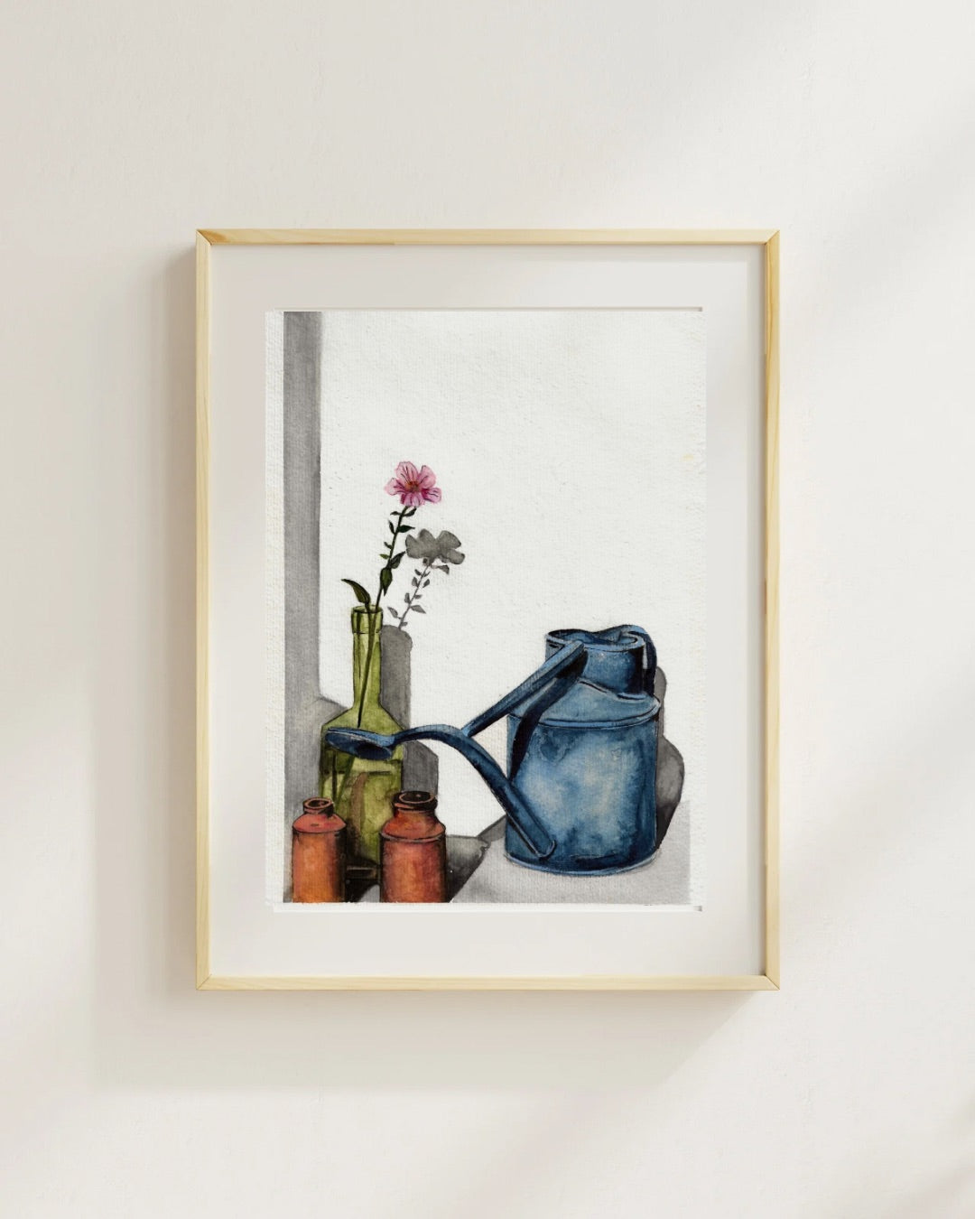 Framed original watercolour painting titled “Watering Can” by Shanaz Minhas, featuring a softly painted watering can in muted tones on white paper.
